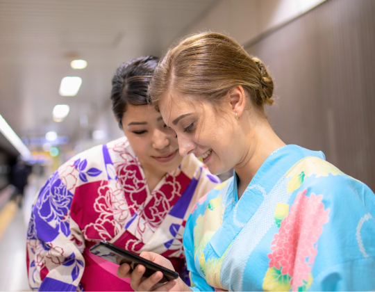 two friends looking at a cell phone and wearing yukata