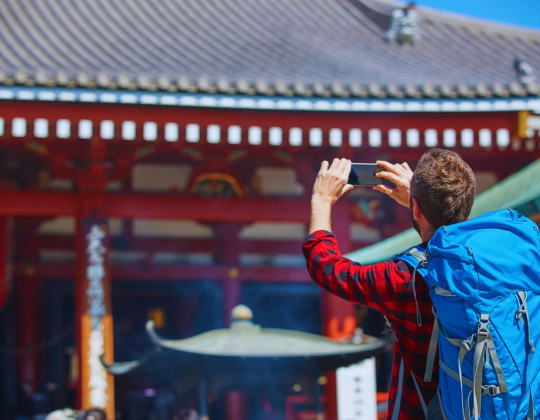  a tourist taking a photo of a japanese temple.