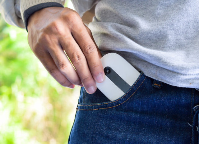 Man pulling pocket wifi router out of his jeans pocket